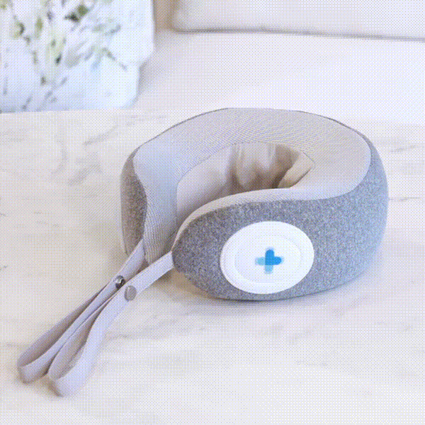 MedMassager neck massager pillow with heat therapy and blue button on a white bed.