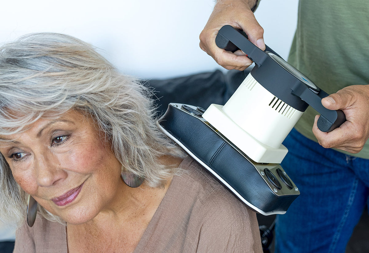 Woman smiling and relaxed while using a MedMassager body massager on her back.