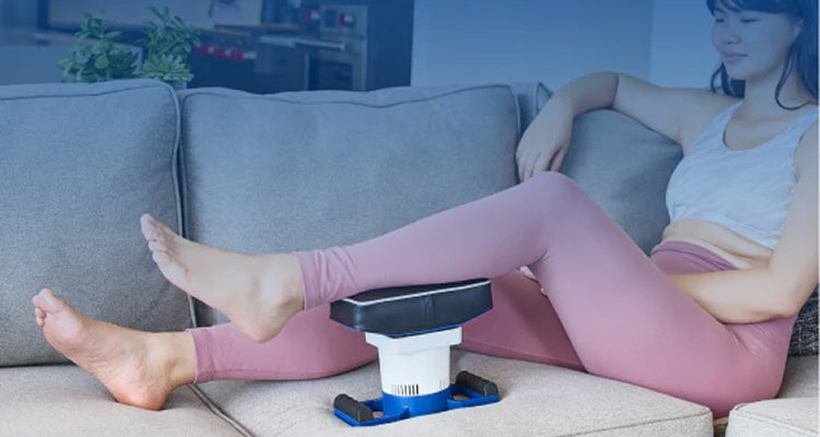 Woman relaxing on a couch with legs resting on a MedMassager foot massager in a comfortable home setting.