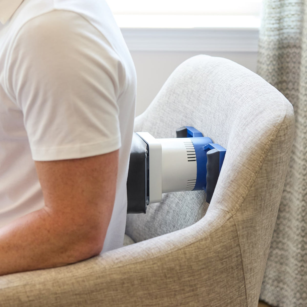 Person using MedMassager body massager on lower back for relaxation.