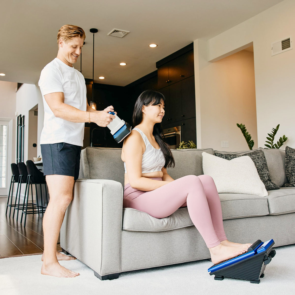 Man using MedMassager body massager on woman’s back as she relaxes at home.