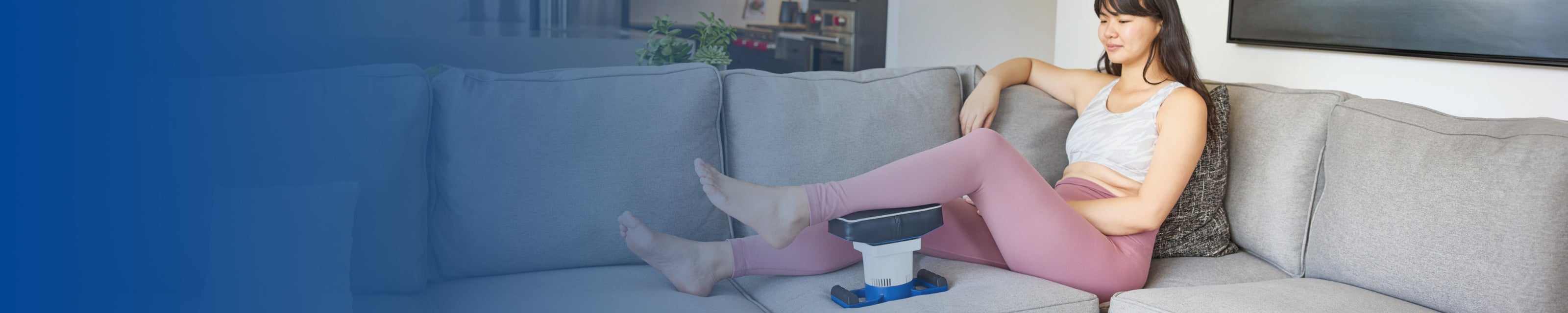 Woman relaxing on sofa in modern living room, using MedMassager leg massager for soothing leg relief.
