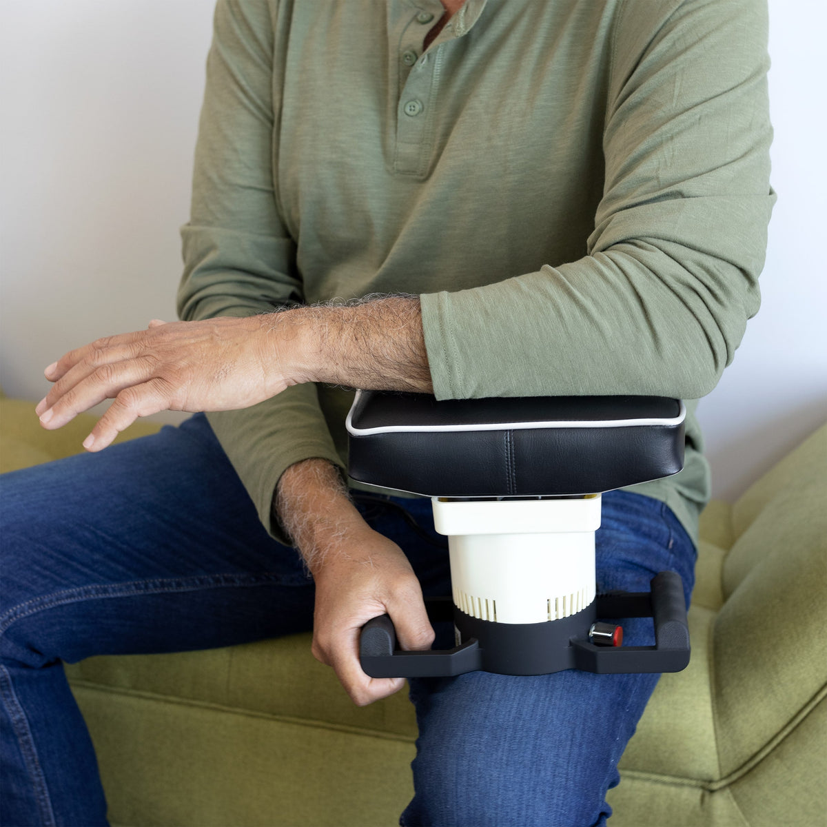 Person in green shirt relaxes on green couch using MedMassager body massager.